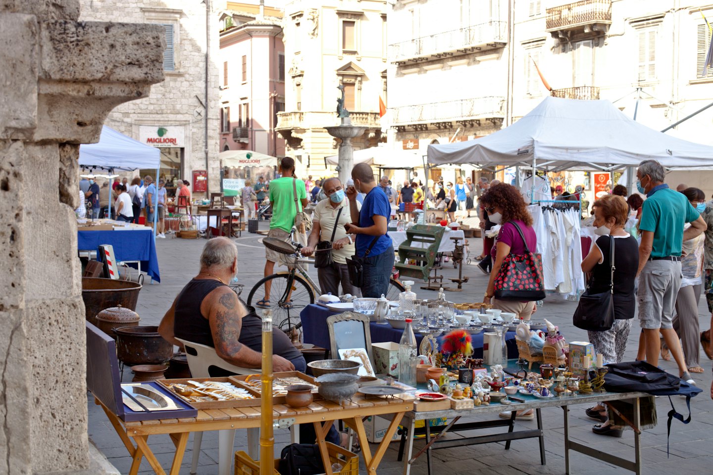 Venditore che vende oggetti d'antiquariato in una bancarella affollata di un mercato all'aperto.