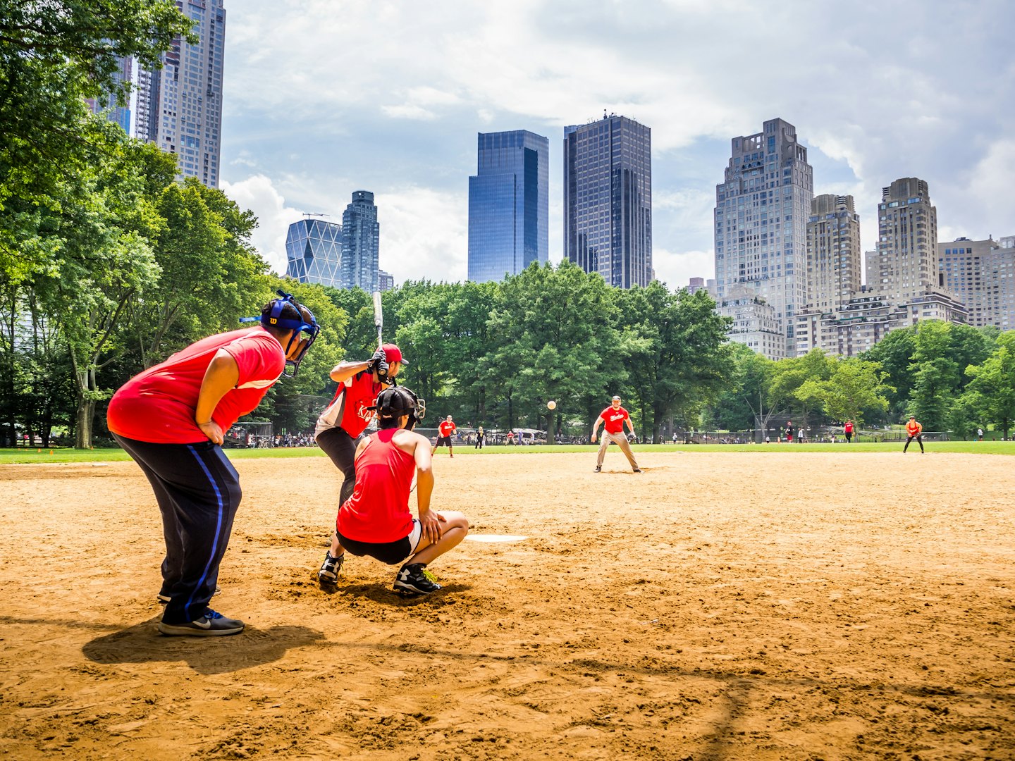 Giocatori che si divertono in una partita di baseball al sole in un parco cittadino.