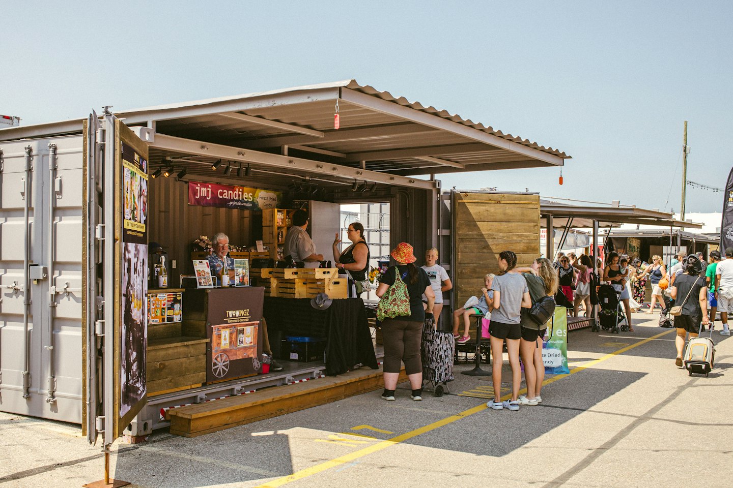 Clienti curiosano tra le bancarelle di un mercato all'aperto di container.